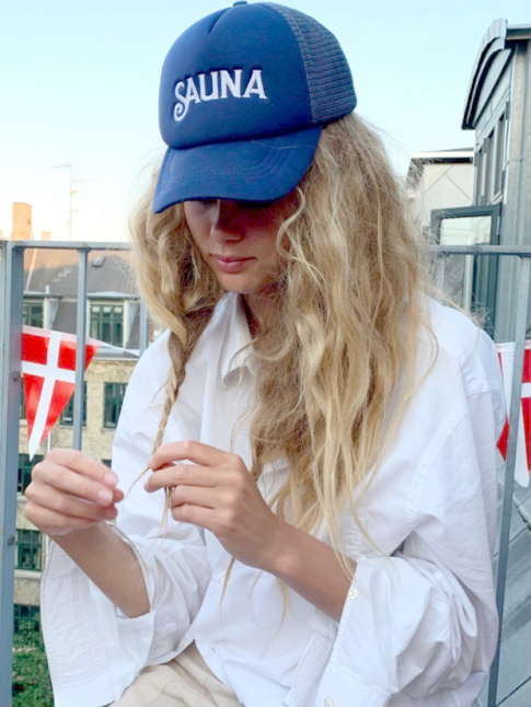 Casquette nineties + longs cheveux blonds emmles + chemise blanche = le bon mix