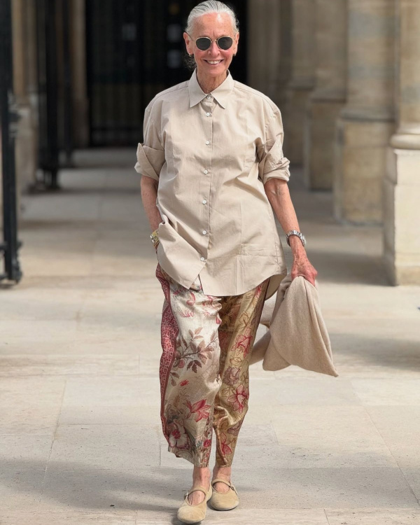 Femme de 70 ans portant une tenue contemporaine avec veste élégante, pantalon clair et accessoires sobres au printemps