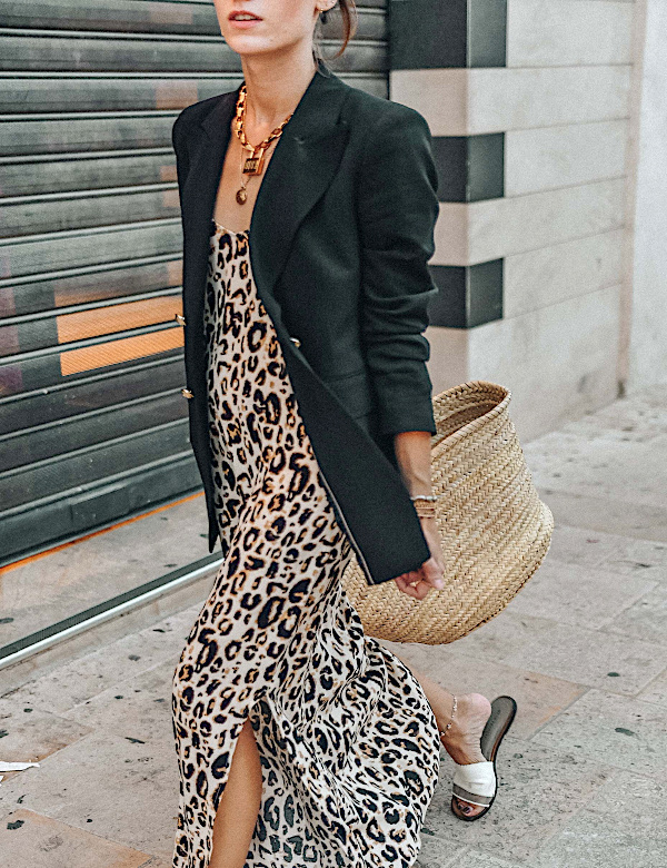 Robe longue léopard portée avec un blazer noir, un panier en osier et des sandales plates blanches