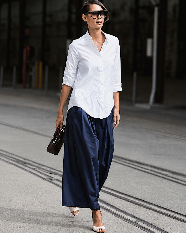 Femme portant une jupe-culotte bleu nuit avec une chemise blanche et un sac structuré