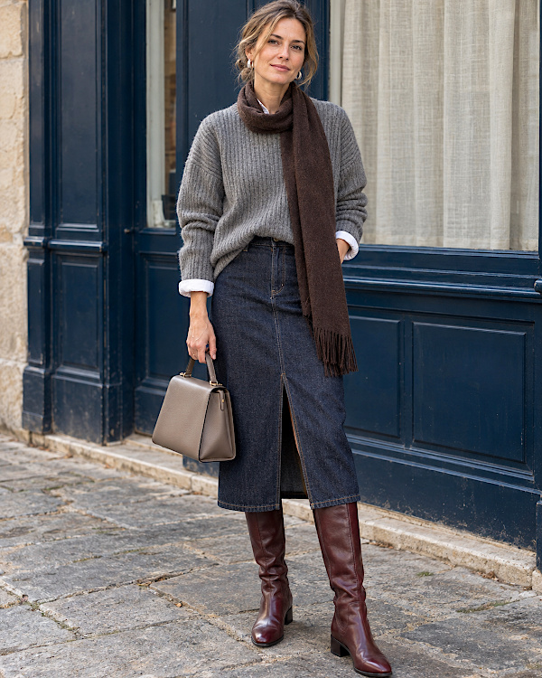 Femme en pull gris, écharpe marron chocolat, jupe midi en jean et bottes bordeaux